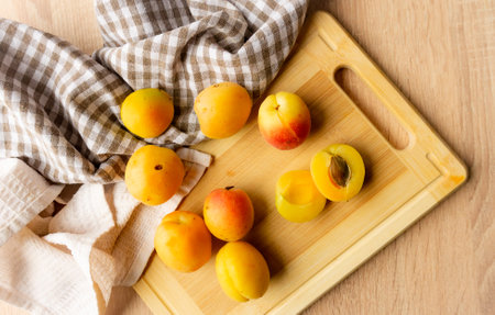 Apricots lying on a wooden board, freshness, harvesting, autumn mood, beautiful decoration with a kitchen towelの写真素材