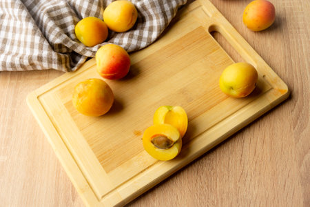 Apricots lying on a wooden board, freshness, harvesting, autumn mood, beautiful decoration with a kitchen towelの写真素材