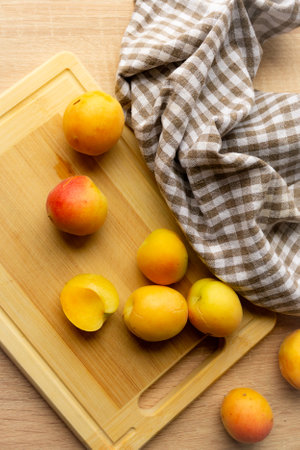 Apricots lying on a wooden board, freshness, harvesting, autumn mood, beautiful decoration with a kitchen towelの写真素材