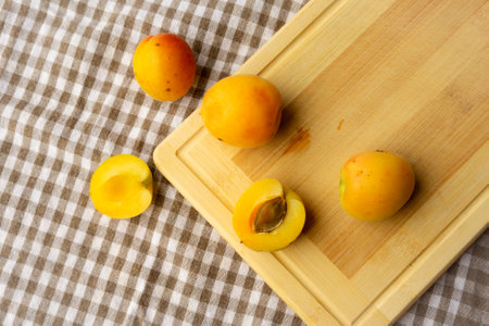 Apricots lying on a wooden board, freshness, harvesting, autumn mood, beautiful decoration with a kitchen towelの写真素材
