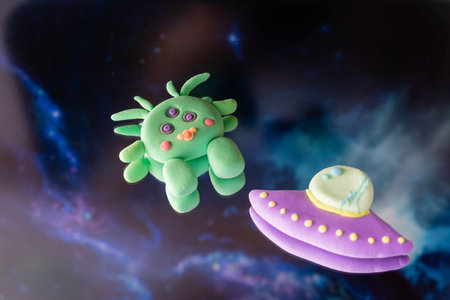 Alien spaceship UFO is flying at night. Clay hand made colorfull figures. Childrens fantasy about...
