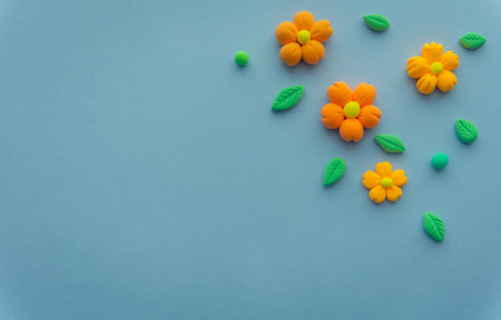 Airy orange flowers with green leaves made of light plasticine, a background with space for your text. Eco theme, plants and gardeningの写真素材