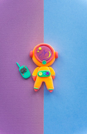 Astronaut made of light Plasticine, Cute and beautiful woman cosmonaut in a helmet with transmitter, Orange suit on bright backgroundの写真素材