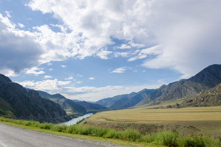 Driving down an empty road with a view of mountains in the distance and cloudy sky through. Road line centerの写真素材