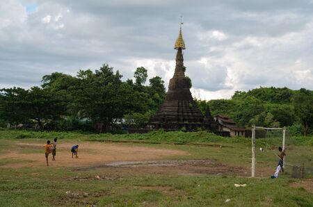 Mrauk-u, Rakhine State / Myanmar - October 18 2016: boys playing football on a muddy field in front of an ancient pagodaのeditorial素材