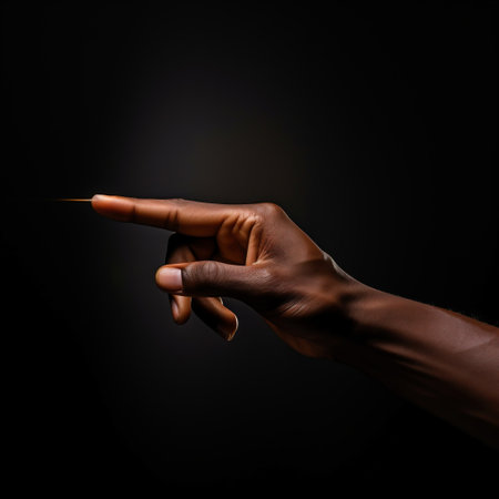 Close-up of human hand pointing with index finger on dark backgroundの素材