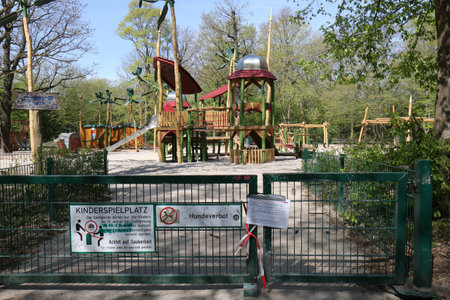 BERLIN, GERMANY - APRIL 16, 2020: Closed Playground in Public Park Hasenheide due to Corona Pandemic (Covid 19) lockdown. Notice by the City of Berlin and barrier tape.のeditorial素材