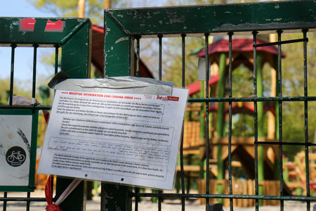 BERLIN, GERMANY - APRIL 16, 2020: Closed Playground in Public Park Hasenheide due to Corona Pandemic (Covid 19) lockdown. Notice by the City of Berlin and barrier tape.のeditorial素材