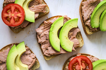 A photo of two toasts with tuna and sliced avocadoの写真素材