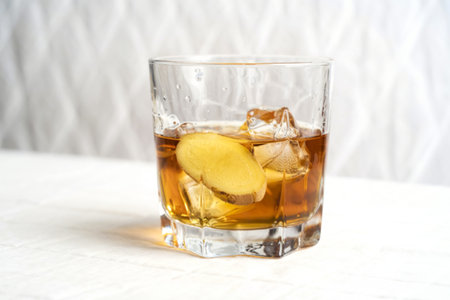 a glass of alcoholic beverage with a ginger root slice
