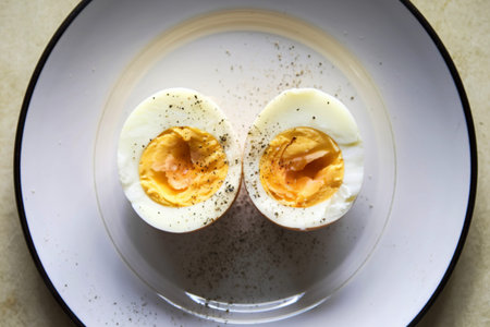 a white plate with two halves of a boiled egg