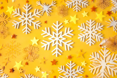 snowflakes and stars against a bright yellow background.の写真素材