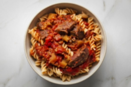 bowl filled with pasta mixed with a rich tomato-based sauce.の写真素材