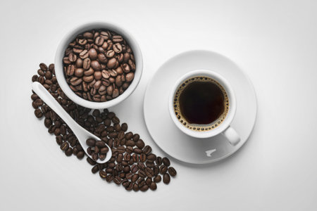 roasted coffee beans surrounding a cup filled with coffeeの写真素材