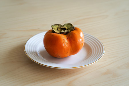 A photograph of a single, perfectly ripe Hachiya persimmonの写真素材