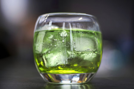 a clear glass filled with a vibrant green beverageの写真素材