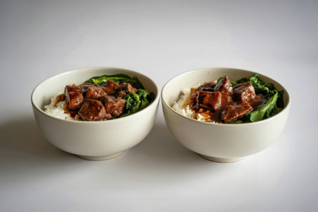 two white bowls with white rice, chunks of beef glazed in sauceの写真素材