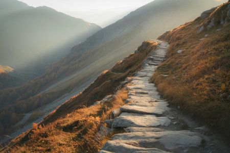 A photograph of a winding stony footpath ascending a rugged mountainsideの写真素材