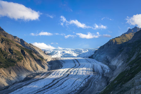 a glacier flowing between mountain slopes under a blue sky