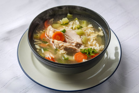 a bowl of chicken soup with rice and vegetablesの写真素材