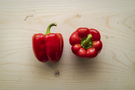 A clean product photography shot of two vibrant red bell peppersの写真素材