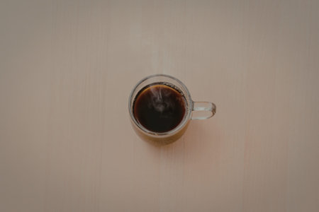 A photograph of black coffee served in a clear glass mug