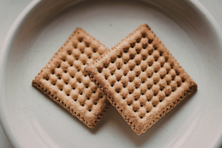 A photo of a pair of square-shaped, brownish crackersの写真素材