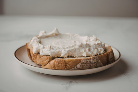 A photo of a bread slice topped with a white cottage cheese spreadの写真素材