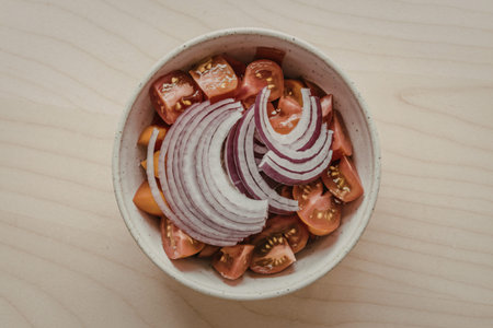 a fresh salad of thinly sliced flat red onions and diced ripe tomatoes