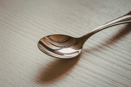 a metallic spoon isolated on a light wooden background