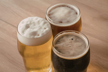 three tall glasses filled with ice-cold golden beerの写真素材