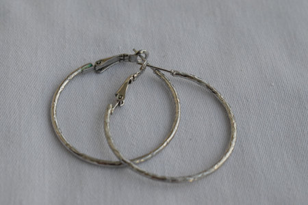Silver hoop earrings on a white background. Goods for creativity and needlework.の写真素材