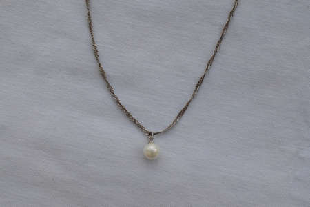 Pearl pendant on a chain on a white background. Goods for creativity and needlework.の写真素材