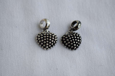 Silver pendants in the shape of a heart on a white background. Goods for creativity and needlework.の写真素材