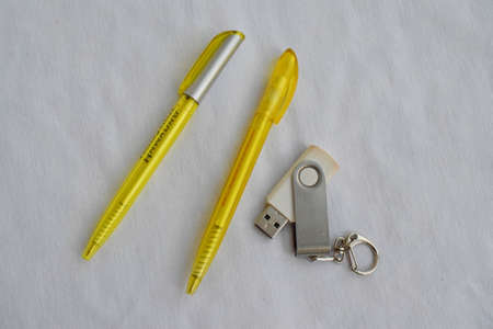 Stationery. Two yellow pens and a flash drive on a white background. The view from the top.の写真素材