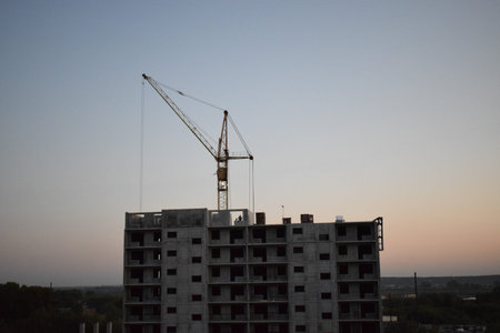 Construction of a multi-storey building at sunset. The crane is working. Industrial landscape.