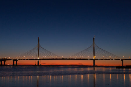 Large suspension bridge over the Neva River and the Bay in St. Petersburg, Russia, at sunset