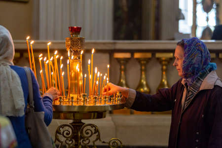 St. Petersburg, Russia, July 12, 2018. A believing Orthodox woman puts a candle in the church in the Alexander Nevsky Lavraのeditorial素材