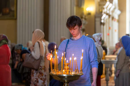St. Petersburg, Russia, July 12, 2018. A believing Orthodox young man puts a candle in the church in the Alexander Nevsky Lavraのeditorial素材