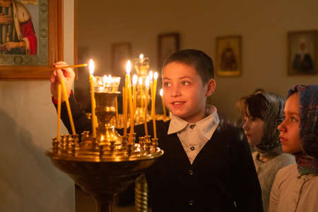 December 9, 2019, St. Petersburg, Russia. A happy smiling boy lights a candle in the Churchのeditorial素材