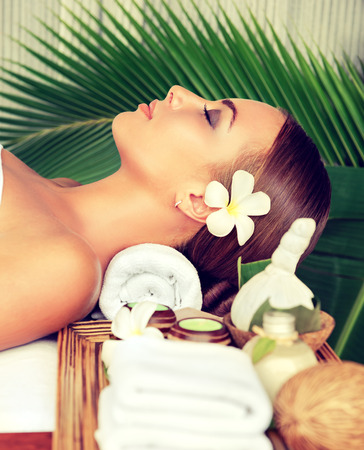 Portrait of young girl who lays on massage table, surrounded comfortable atmosphere of spa-salon. Beauty and Spa treatment concept.の写真素材