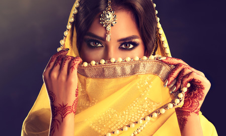 Beautiful indian girl . Young hindu woman model  with tatoo mehndi  and kundan jewelry . Traditional Indian costume, yellow saree.の写真素材