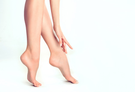 Perfect womans fingers with colorless manicure touch well-groomed feet.Spa ,scrub and foot care.の写真素材