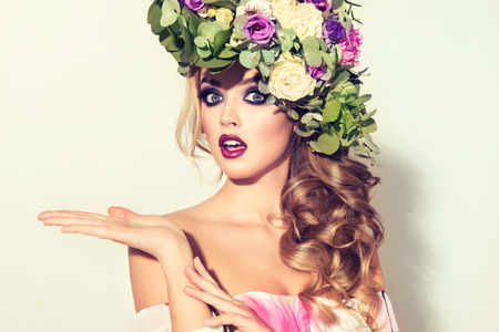 Lady Spring.Beautiful model with flower wreath on his head demonstrate imaginary product. Makeup-smoky eyes style.の写真素材