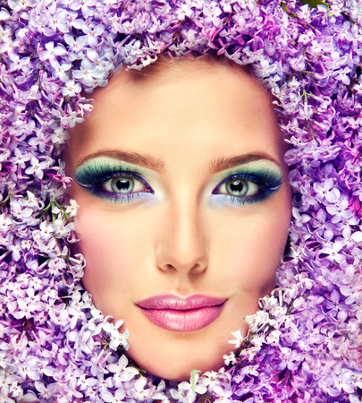 Gorgeous womans face surrounded by lilac flowers.Bright lavender-color make up.の写真素材