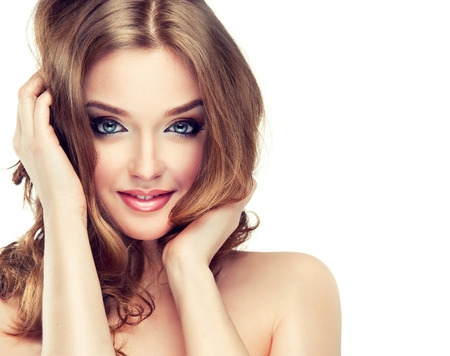 Young woman is dressed up in a  vivid make up, is touching own face and hair. Attractive woman with face full of emotions. Voluminous, shiny and wavy hair,black eyelashes and  gilded eyelids.の写真素材