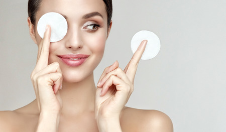 Young beautiful, smiling woman model is holding cotton pads in the fingers. Symbolic image of facial treatment, cosmetology, beauty technologies and spa.の写真素材