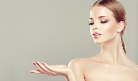 Gorgeous, young woman with clean, fresh skin is holding graceful hand in front ownself. Beauty and cosmetology.の写真素材