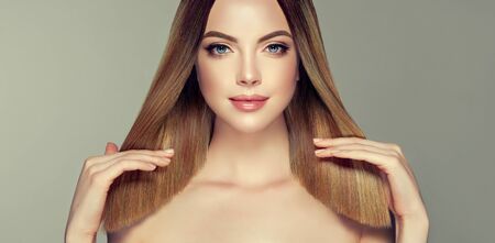 Young and pretty woman with soft smile on the face in demonstrating perfectly looking, middle length straight, shiny hair. Trendy hairstyle. Hair care and hairdressing art.の写真素材