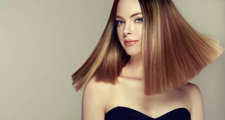 Young and pretty woman with soft smile on the face in demonstrating perfectly looking, middle length straight, shiny hair. Trendy hairstyle. Hair care and hairdressing art.の写真素材